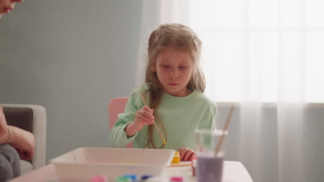 Serious little girl draws Ebru art with sister at workshop