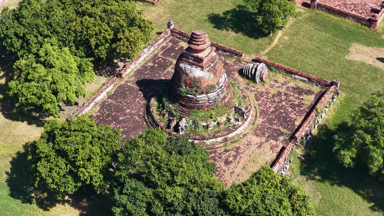 Ripresa aerea dall'alto di un antico stupa in mattoni circondato da alberi verdi ed erba
