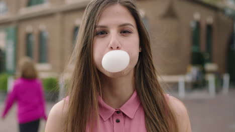 slow motion portrait of young beautiful woman student blowing bubble gum wearing pink shirt