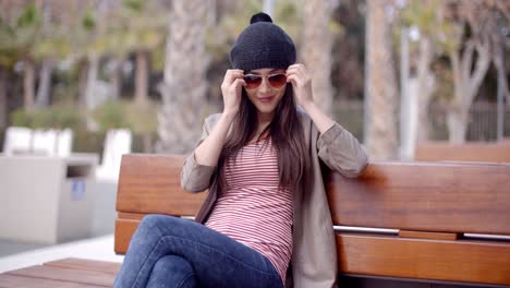 Mujer-Joven-De-Moda-Relajándose-En-Un-Banco-Del-Parque