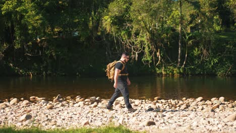 male hiker walking by a rocky river in the jungle