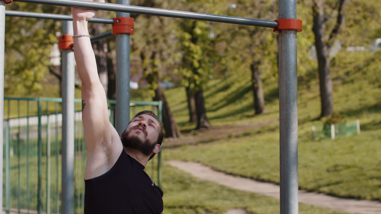 Athletic lebanese man in sportswear doing pull ups exercises on horizontal bar pumping up back