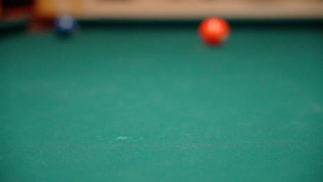 slow motion billiards cue ball hits green 6 ball with spin and full contact close up on pool table with green felt from a low angle