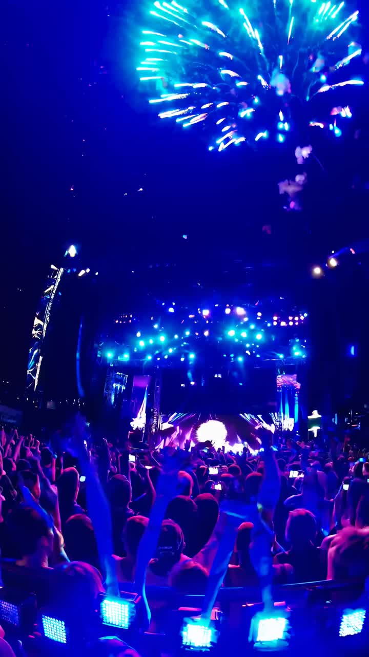 Dynamisk video af en koncert om natten, optaget fra en lav engel, der viser et farverigt fyrværkeri