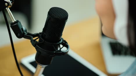 micrófono de condensador de primer plano del creador de contenido mujer anfitriona transmitiendo su podcast en portátil con auriculares conversación de entrevista en el estudio de transmisión en casa. blogger grabando voz por radio.