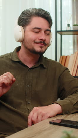 middleaged man enjoys music with smartphone headphones nodding head rhythm relaxed content at table