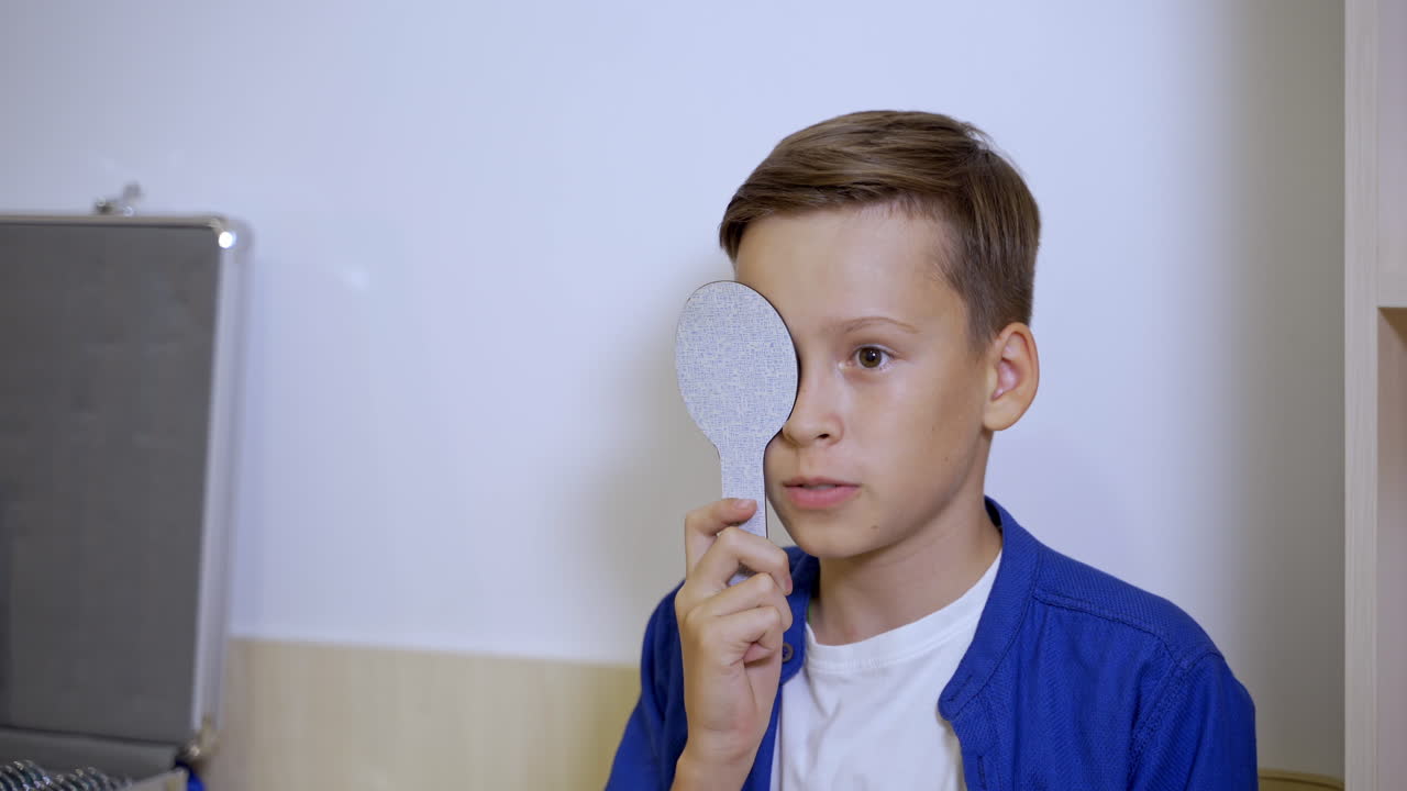 Examining eyesight of a kid patient with with ophthalmology plate. Pediatric concept.