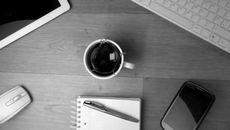 Two-sugar-cubes-falling-into-cup-of-coffee-and-splashing-a-keyboard-in-black-and-white