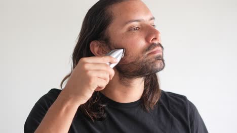 Latino-man-trimming-beard-and-mustache-with-electric-razor,-Beard-scissors