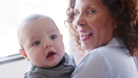 baby grandson looking over grandmothers shoulder as she cuddles him