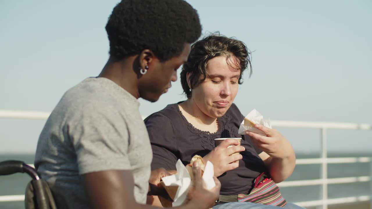 pareja feliz con discapacidad comiendo pasteles y bebiendo café