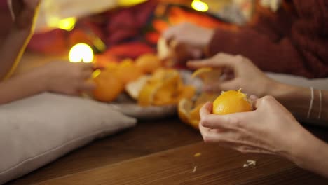 close up of hands, family taking mandarins under christmas tree in lights