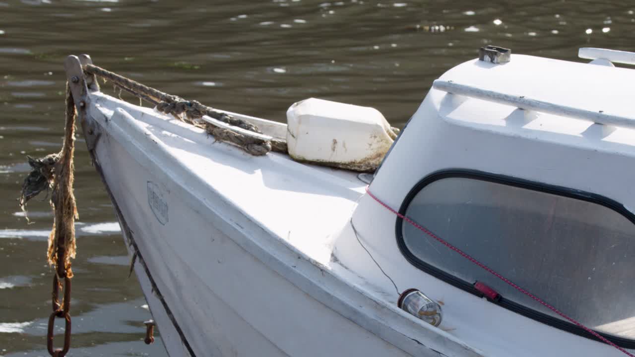 White motorboat gently floating, close-up view, calm daylight, minimal camera movement, reflective water surface