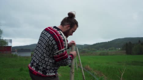 man pulling up wooden fence post at the field