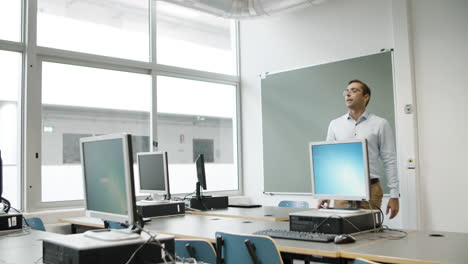 middle-aged male teacher talking to students in computer lab