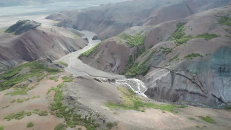 Aerial-view-of-the-colorful-mountains-in-Hvannagil-during-summer-in-Iceland,-showcasing-the-vibrant-rhyolite-formations-and-rugged-landscape