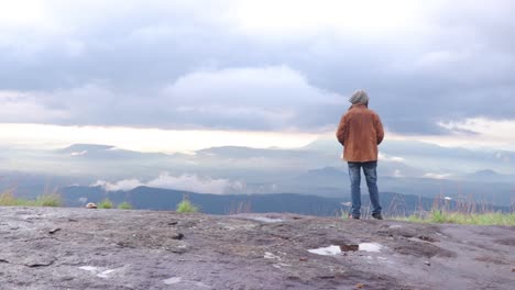 joven parado en la cima del acantilado disfrutando de la vista de la naturaleza