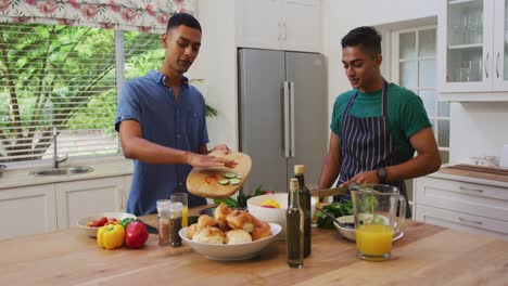 Feliz-Pareja-Masculina-Gay-De-Raza-Mixta-Hablando-Y-Preparando-Comida-En-La-Cocina