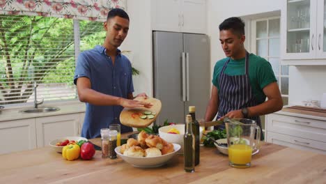 pareja de hombres gay de raza mixta feliz hablando y preparando comida en la cocina