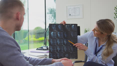 Woman-Doctor-Or-GP-In-Office-With-Male-Patient-Looking-At-CT-Or-MRI-Scan