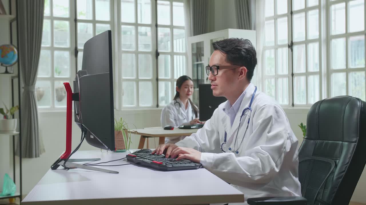 Young Asian Man Doctor Is Using Desktop Computer In Workplace. Medical Concept