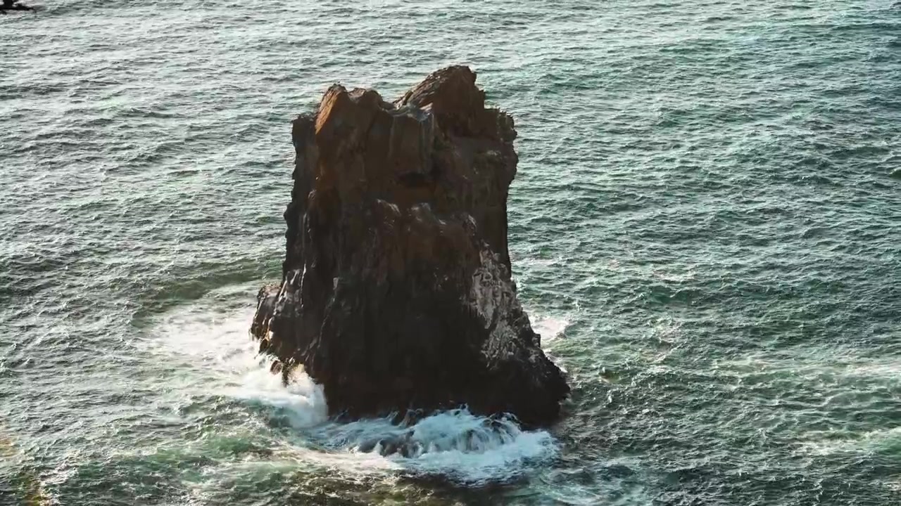 Grande farilhão em Cannon Beach ao longo da costa do Oregon, com ondas do oceano quebrando contra ele.