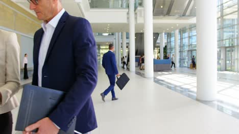 Multi-ethnic-business-people-discussing-over-digital-tablet-in-the-office-lobby-4k