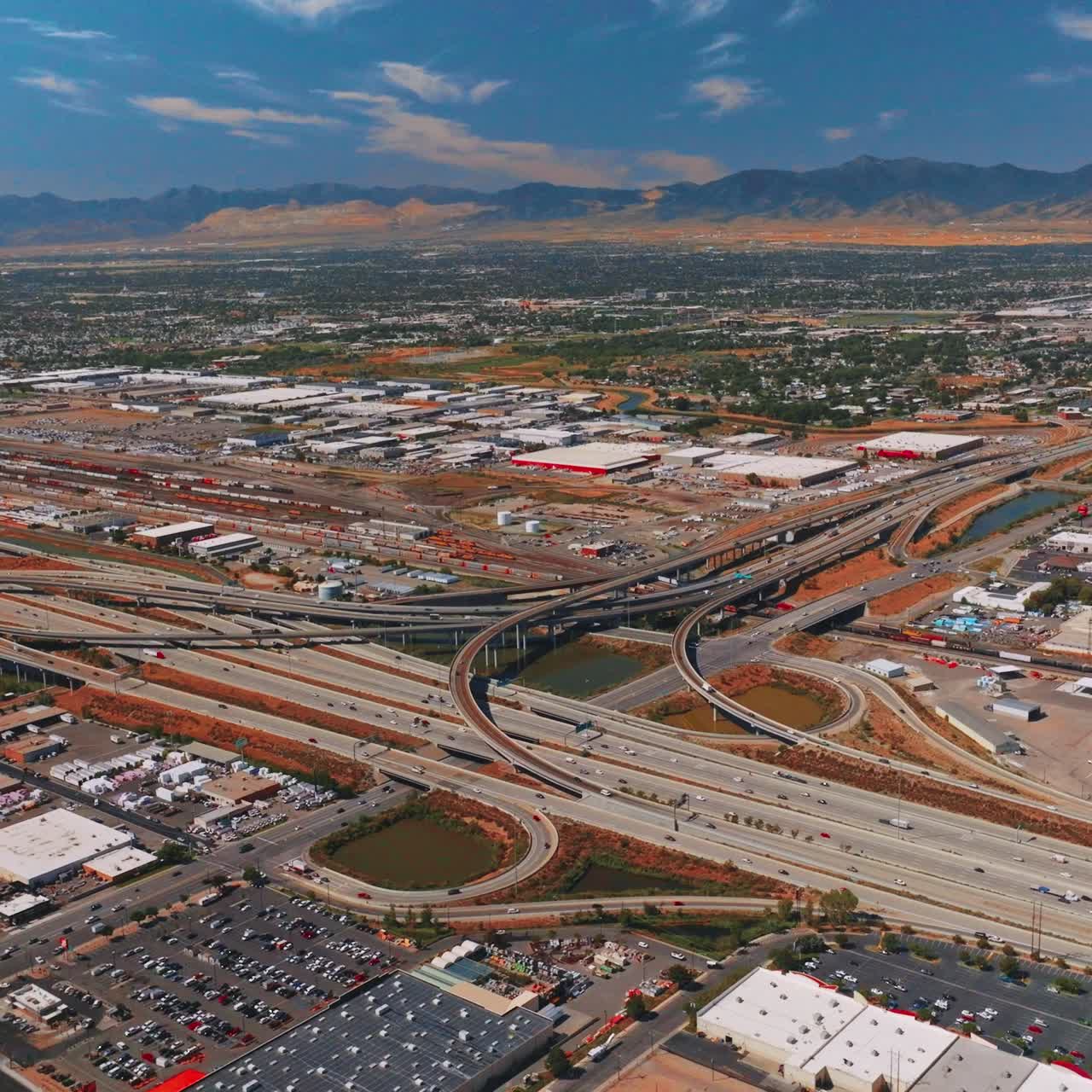 Complicated system of roads in Salt Lake City. Vast city scenery at backdrop of mountains at daytime. Top view