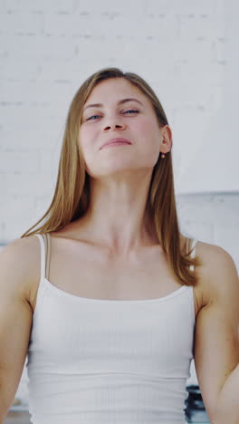 lovely woman in the modern kitchen. young happy female holding halves of oranges and closes her eyes by them. healthy lifestyle. vertical video