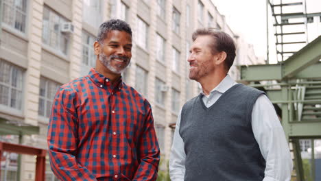 Two-middle-aged-male-work-colleagues-outside-their-workplace