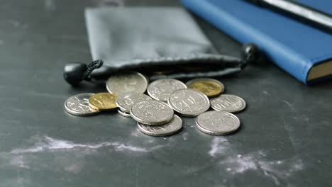 monedas, cuaderno y bolígrafo en una superficie oscura