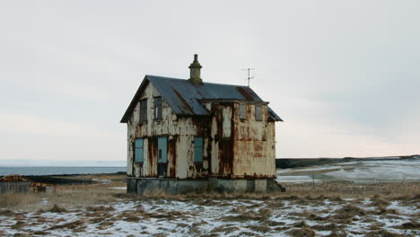 a quiet, stable view of an old, abandoned house standing alone by the sea