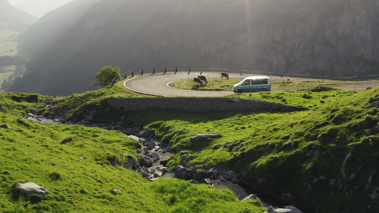 은색 미니밴 캠퍼가 휘어지는 에픽 스위스 로드 곡선을 따라 운전하고 있습니다.