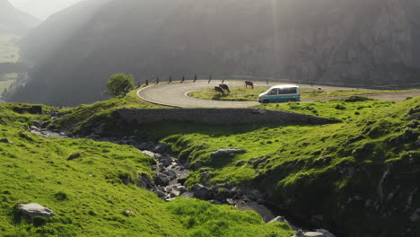Silver-minivan-camper-driving-down-winding-epic-Swiss-road-bend