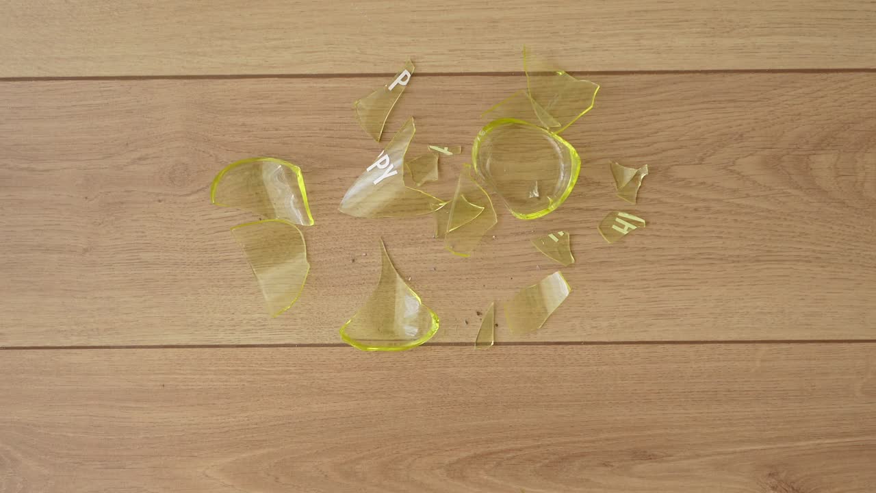 Broken Yellow Glass on Wooden Floor