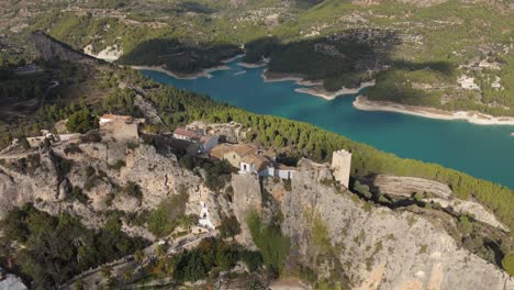 reverse drone view of the castle of guadalest and the blue lake, revealing the landscape