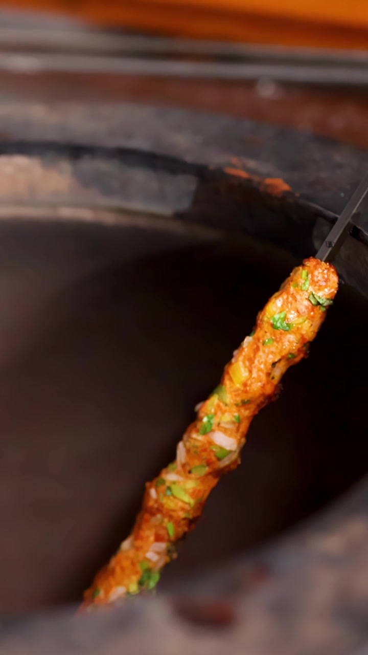 Seekh Kebab in cottura su uno spiedo in un forno tandoor.