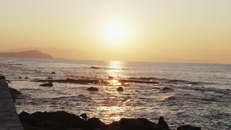 slow motion shot of sunset over ocean waves crashing against stones, beautiful aegean sea background in chania, crete greece