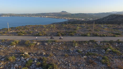 Turistas-Montando-Ciclomotores-A-Lo-Largo-De-La-Carretera-Con-El-Mar-De-Fondo