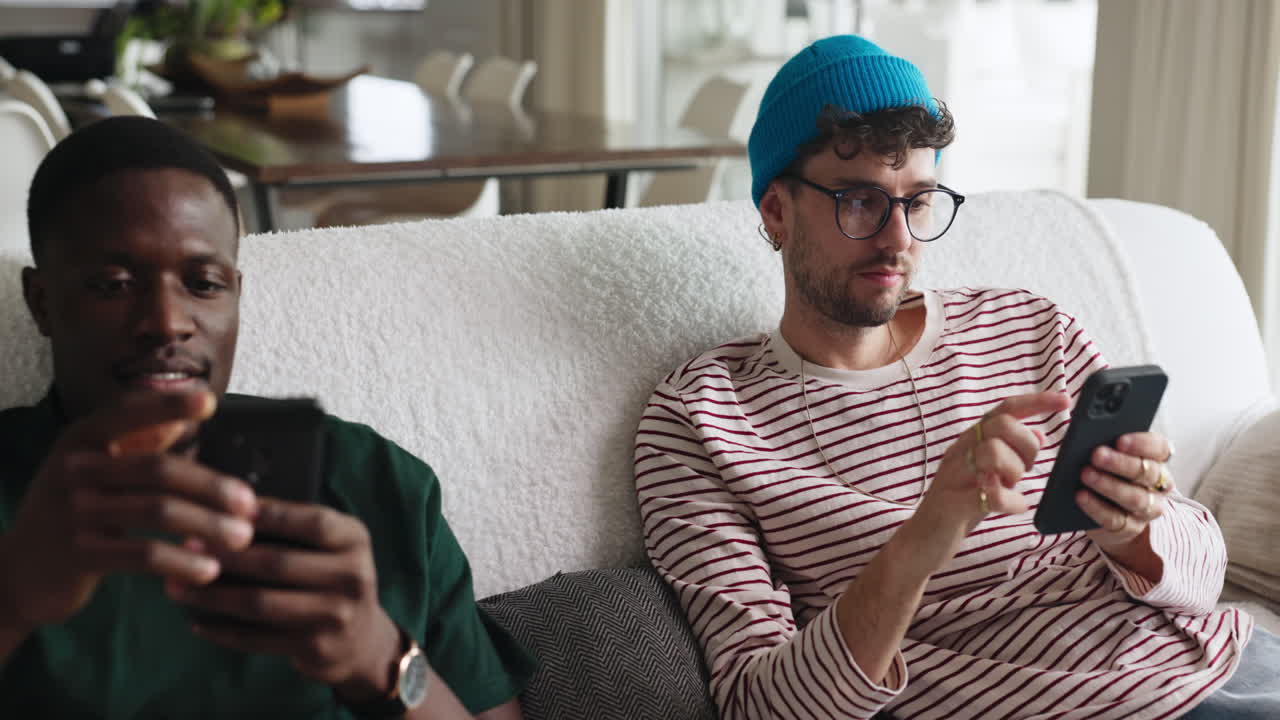 Two friends looking at phones on a couch