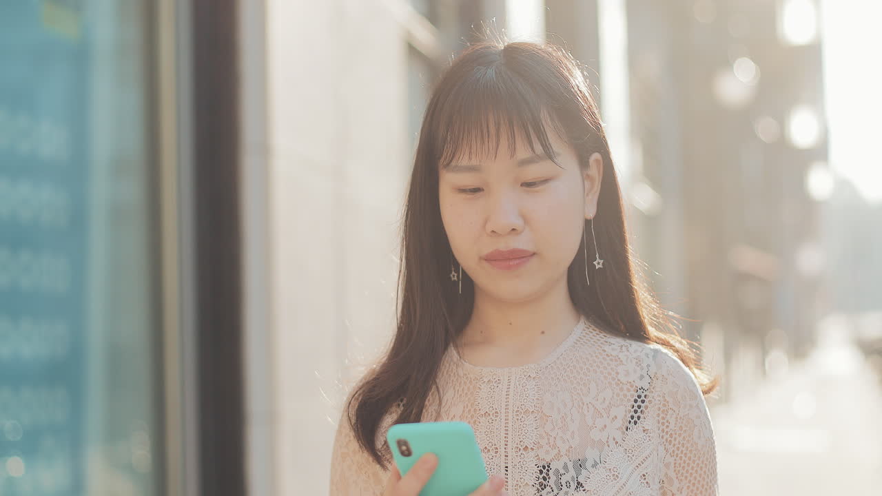 Asian woman using phone on street