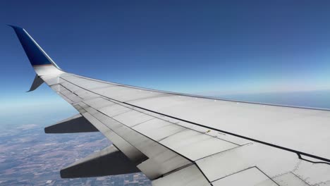 pedestal-tile shot of a beautiful view out of an airplane's window on a clear blue day while flying