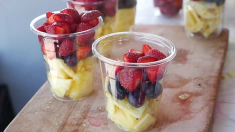 close up of a fruit salad with strawberries, pineapple and grapes in a clear plastic cup