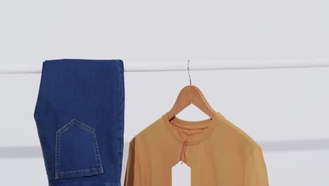 video of denim trousers and yellow t shirt on hanger and copy space on white background