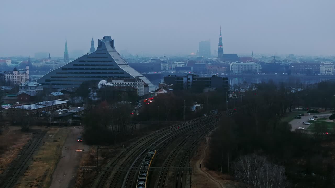 A foggy winter morning as yellow train enters Riga near National Library Latvia