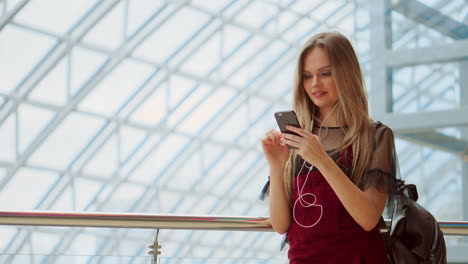 Girl-use-mobile-phone,-blur-image-of-inside-the-mall-as-background.