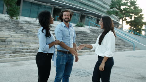 joven barbudo y su colega negro sonriendo y estrechando la mano del solicitante de empleo