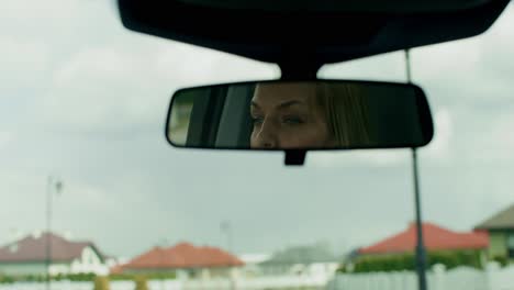 woman driving a car, viewed in a rearview mirror