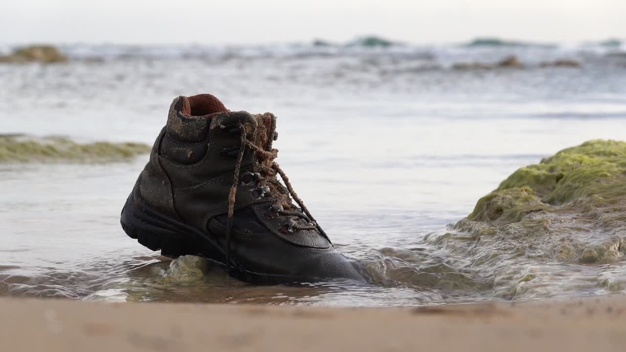 Abandoned shoe as a garbage on a sangy beach in Sicily, Italy with slight slow-motion effect