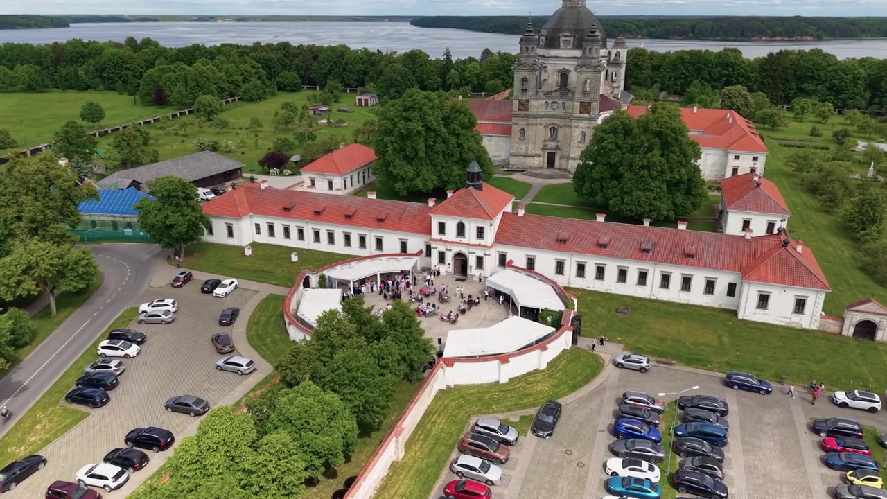 Upea dronevideo leijuu Pazaislisin luostarin yllä Kaunasissa, Liettuassa, näyttäen väkijoukkoja, pysäköityjä autoja ja reheviä puistoalueita kirkkaana päivänä. Terävä ilmakuva tallentaa vilkasta toimintaa.